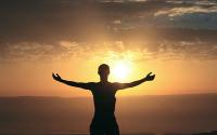 Dark Outline of a woman looking at the Sunrise with arms wide open